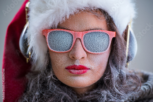 Photo: Woman wearing Santa Claus hat and sunglasses listening to music Woman wearing Santa Claus hat and sunglasses listening to music