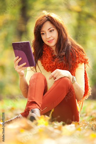 Photo: Young pretty woman with tablet in the autumn park Young pretty woman with tablet in the autumn park