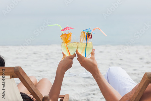 Photo: Couple clinking glasses of cocktail on beach Couple clinking glasses of cocktail on beach