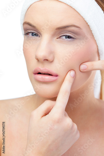 Photo: Blonde model pressing pimple on her cheek Blonde model pressing pimple on her cheek