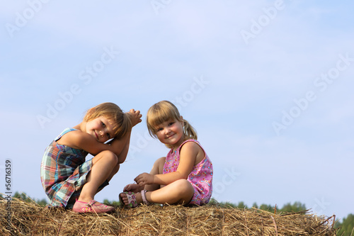 Photo: Two girls sit on haystack Two girls sit on haystack