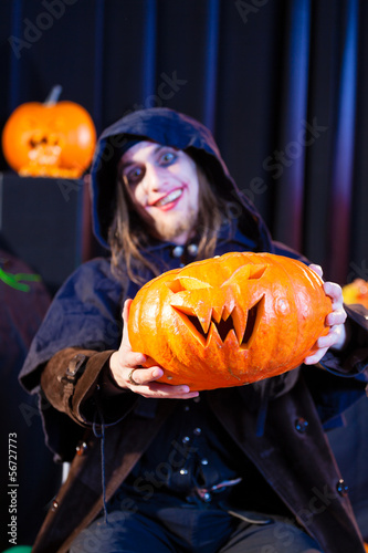 Photo: Man in scary Halloween costume holding pumpkin Man in scary Halloween costume holding pumpkin