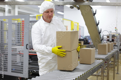 Photo: worker in white apron at packing line in factory worker in white apron at packing line in factory