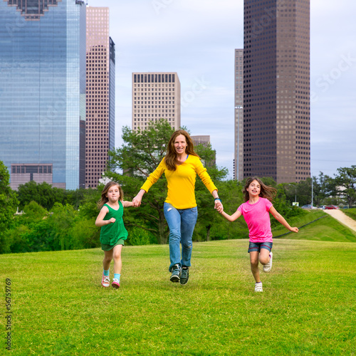 Photo: Mother and daughters walking holding hands on city skyline Mother and daughters walking holding hands on city skyline