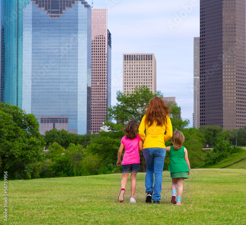 Photo: Mother and daughters walking holding hands on city skyline Mother and daughters walking holding hands on city skyline