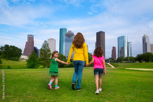 Photo: Mother and daughters walking holding hands on city skyline Mother and daughters walking holding hands on city skyline