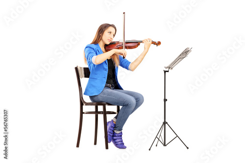 Photo: Young woman on a wooden chair playing the violin Young woman on a wooden chair playing the violin
