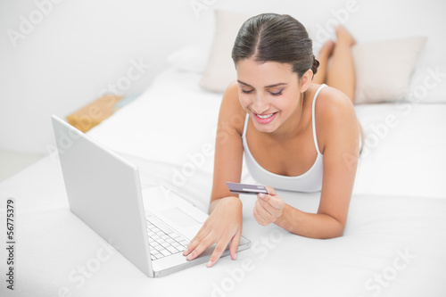 Photo: Dreamy young brown haired model in white pajamas shopping online Dreamy young brown haired model in white pajamas shopping online