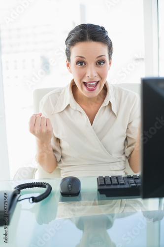 Photo: Joyful stylish brunette businesswoman raising her fists Joyful stylish brunette businesswoman raising her fists