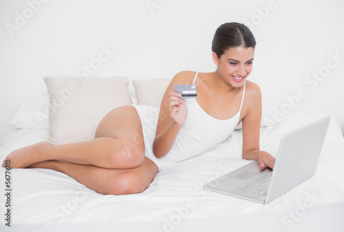 Photo: Pretty young brown haired model in white pajamas shopping online Pretty young brown haired model in white pajamas shopping online