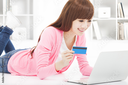 Photo: young woman online shopping at home with credit card young woman online shopping at home with credit card