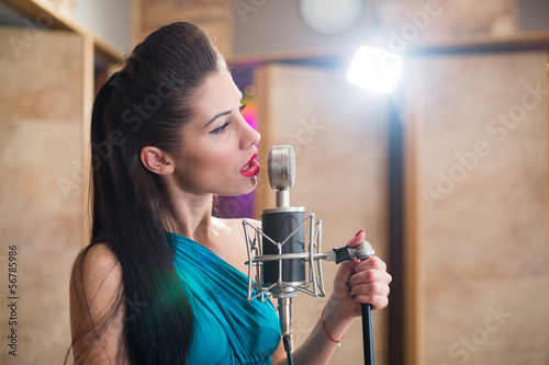Photo: Beautiful girl with red lips holding a microphone and singing Beautiful girl with red lips holding a microphone and singing