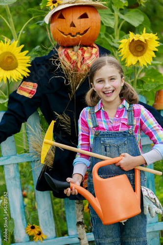 Photo: Scarecrow and happy girl in the garden Scarecrow and happy girl in the garden