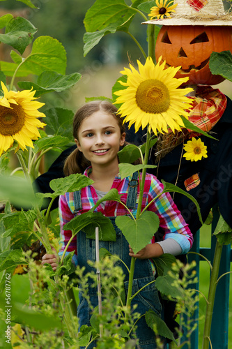 Photo: Scarecrow and happy girl in the garden Scarecrow and happy girl in the garden