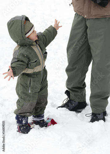 Photo: Child in winter snow with parent Child in winter snow with parent