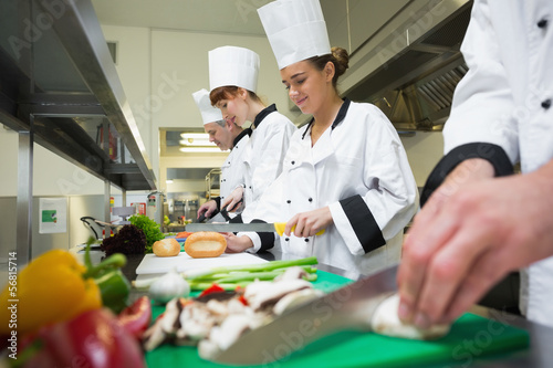Photo: Four chefs preparing food at counter in a row Four chefs preparing food at counter in a row