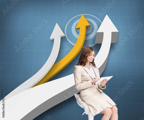 Photo: Pleased businesswoman using a tablet pc sitting on a bar chair Pleased businesswoman using a tablet pc sitting on a bar chair