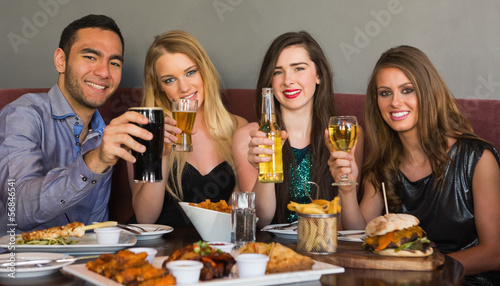 Photo: Friends having dinner together smiling at camera Friends having dinner together smiling at camera