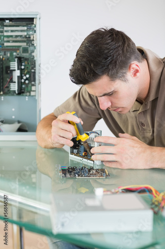 Photo: Handsome focused computer engineer repairing hardware with plier Handsome focused computer engineer repairing hardware with plier