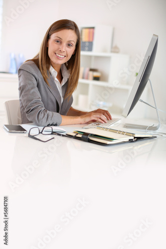Photo: Saleswoman in office working on desktop computer Saleswoman in office working on desktop computer
