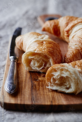 Photo: Croissant and a table knife on wooden chopping board Croissant and a table knife on wooden chopping board