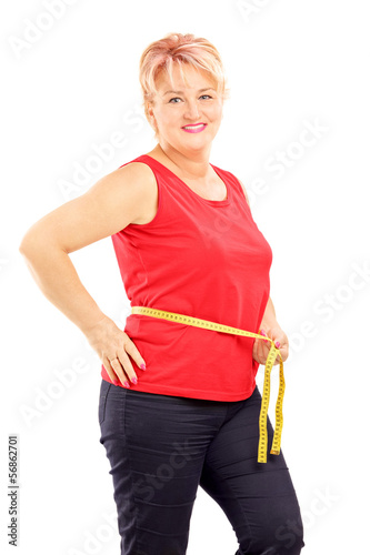 Photo: Smiling mature woman measuring her waist after diet Smiling mature woman measuring her waist after diet