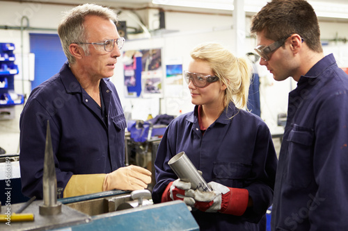 Photo: Engineer Working With Apprentices On Factory Floor Engineer Working With Apprentices On Factory Floor