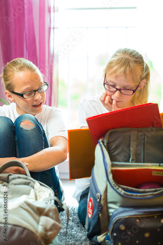 Photo: Girls doing homework and packing school bags Girls doing homework and packing school bags