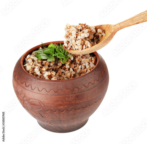 Photo: Buckwheat in pot and wooden spoon isolated on white Buckwheat in pot and wooden spoon isolated on white