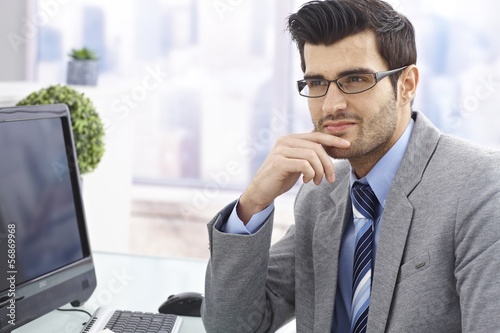 Photo: Handsome businessman sitting at desk Handsome businessman sitting at desk