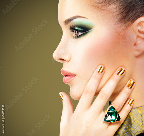 Photo: Glamour woman with beautiful golden nails and emerald ring Glamour woman with beautiful golden nails and emerald ring