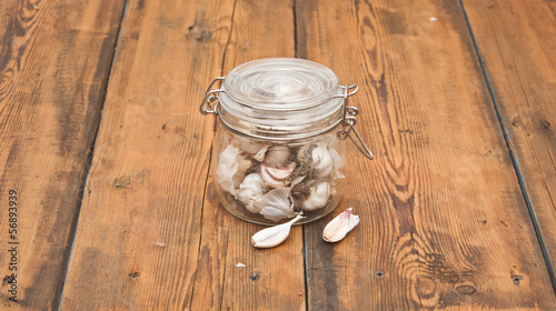 Photo: fresh garlic in glass jar on old wooden table fresh garlic in glass jar on old wooden table