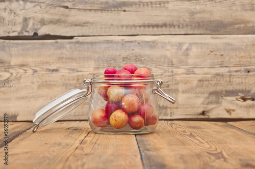 Photo: freshly picked plum in glass jar on old wooden table freshly picked plum in glass jar on old wooden table
