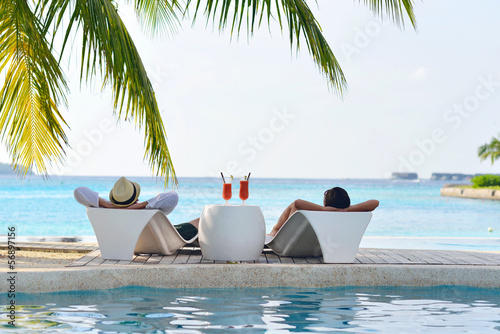 Photo: happy young couple relax and take fresh drink on poolside happy young couple relax and take fresh drink on poolside