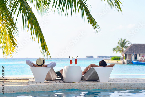 Photo: happy young couple relax and take fresh drink on poolside happy young couple relax and take fresh drink on poolside