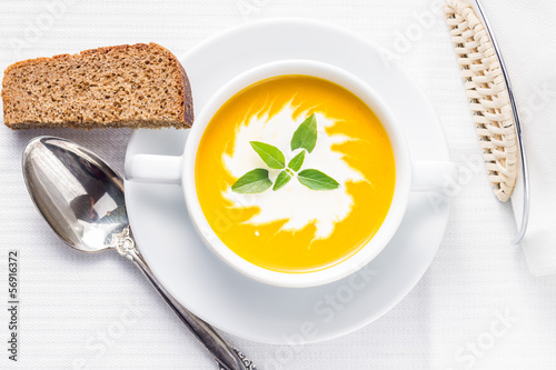 Photo: Pumpkin soup with basil on served table Pumpkin soup with basil on served table