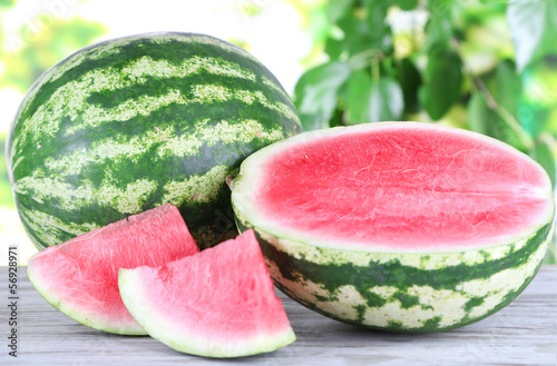 Photo: Ripe watermelons on wooden table on nature background Ripe watermelons on wooden table on nature background