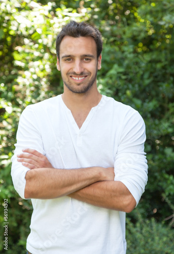 Photo: Laughing latinman with crossed arms in a park Laughing latinman with crossed arms in a park