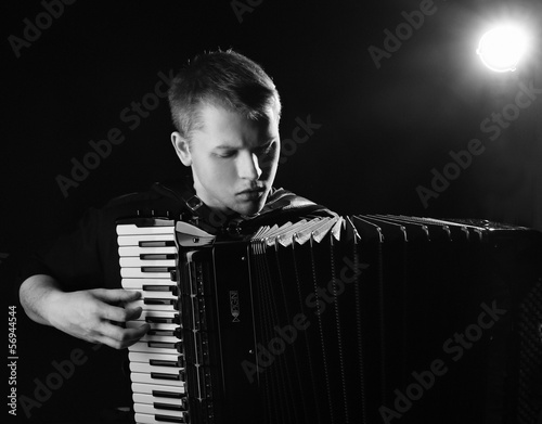 Photo: musician plays the accordion against a dark background musician plays the accordion against a dark background