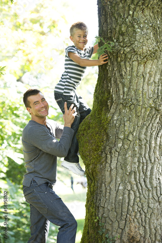 Photo: Father holding son while he climbs a tree Father holding son while he climbs a tree