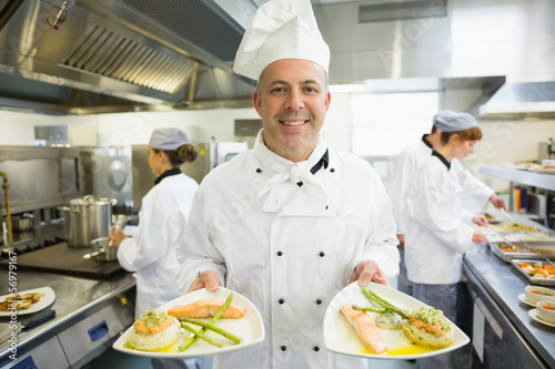Photo: Mature head chef presenting proudly some dinner plates Mature head chef presenting proudly some dinner plates