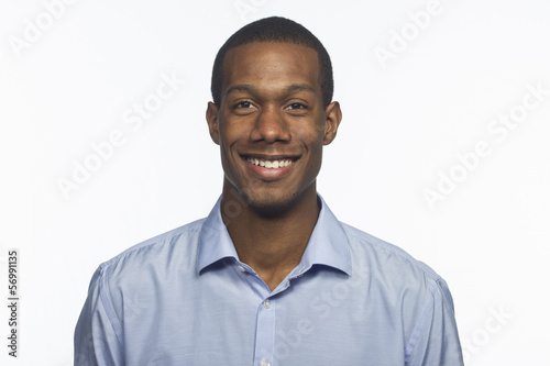 Photo: Young black man smiling against white background Young black man smiling against white background