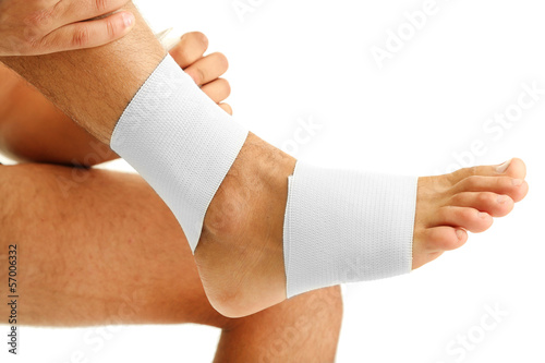 Photo: Young man with elastic bandage on leg, isolated on white Young man with elastic bandage on leg, isolated on white