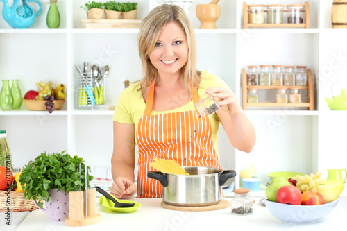 Photo: Happy smiling woman in kitchen preparing for healthy meal Happy smiling woman in kitchen preparing for healthy meal