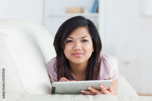 Photo: Woman typing on a tablet while resting on a couch Woman typing on a tablet while resting on a couch
