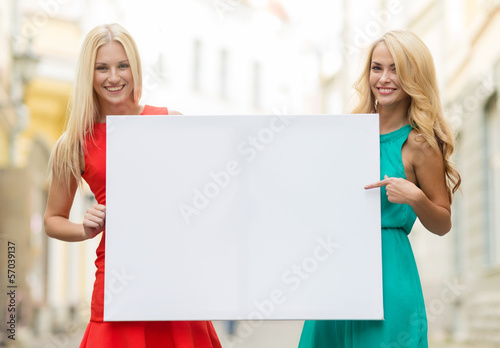 Photo: two happy blonde women with blank white board two happy blonde women with blank white board