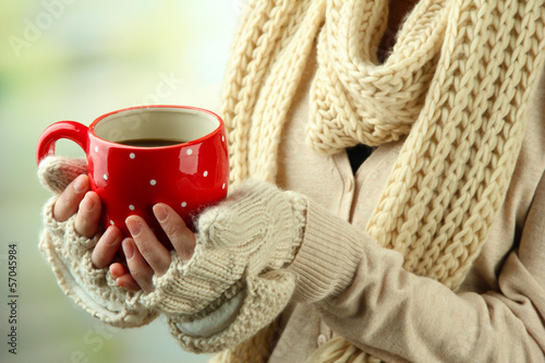 Photo: Female hands with hot drink, on light background Female hands with hot drink, on light background