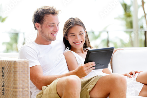 Photo: Couple relaxing together in sofa with tablet pc Couple relaxing together in sofa with tablet pc