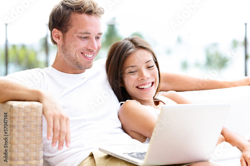 Photo: Couple in sofa with laptop pc at home laughing Couple in sofa with laptop pc at home laughing
