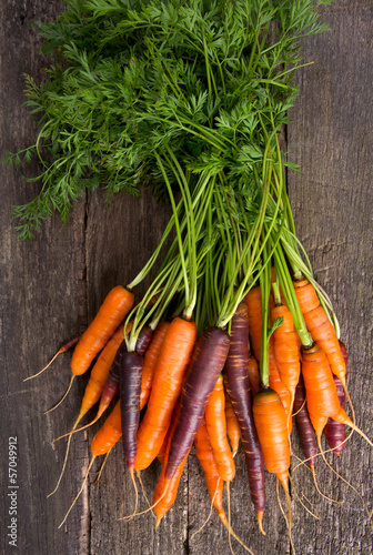 Photo: colored carrots on wooden surface colored carrots on wooden surface